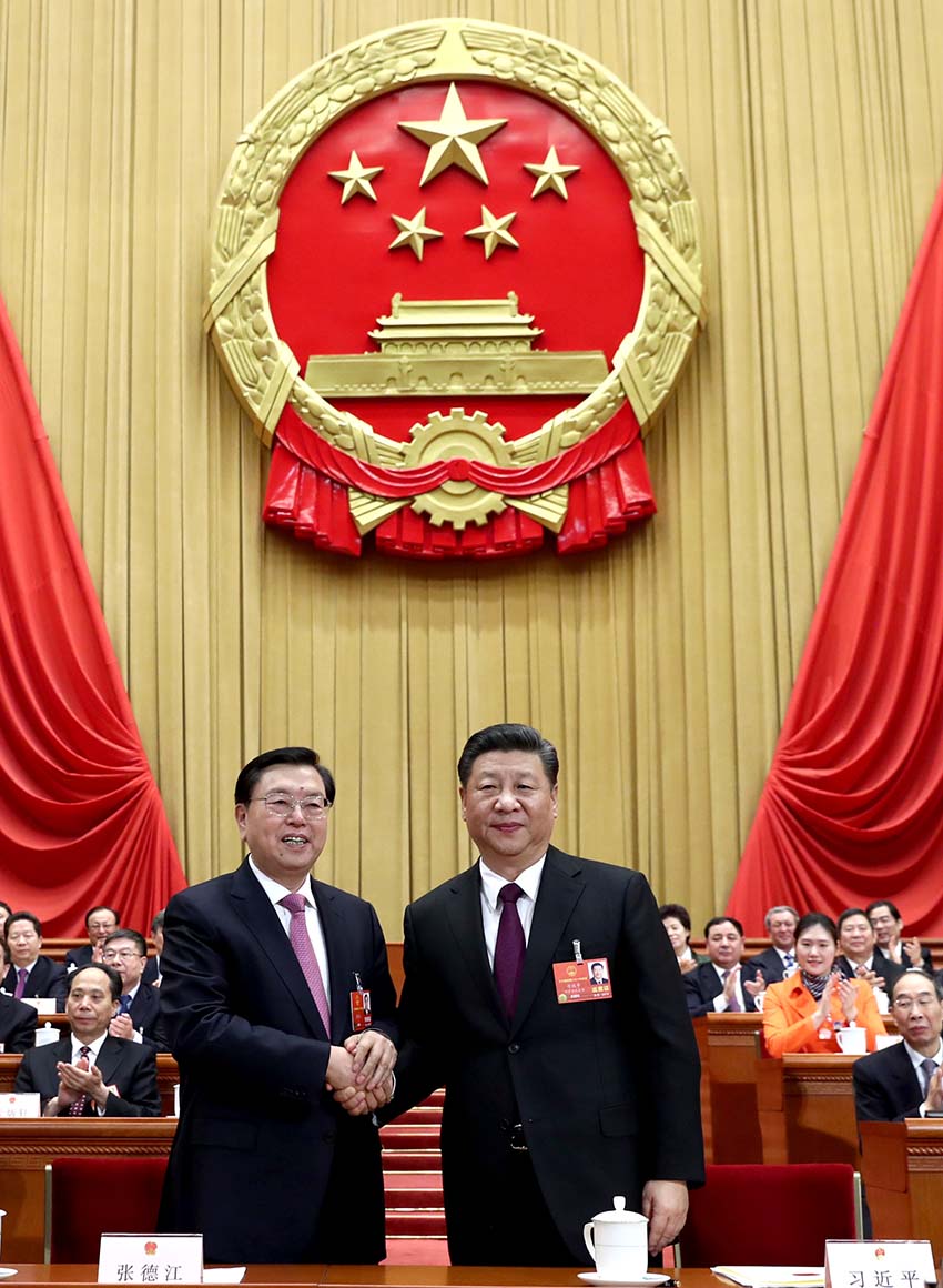 3月17日，十三屆全國人大一次會議在北京人民大會堂舉行第五次全體會議。習近平當選中華人民共和國主席、中華人民共和國中央軍事委員會主席。這是習近平在主席台上同十二屆全國人大常委會委員長張德江握手。新華社記者 鞠鵬 攝