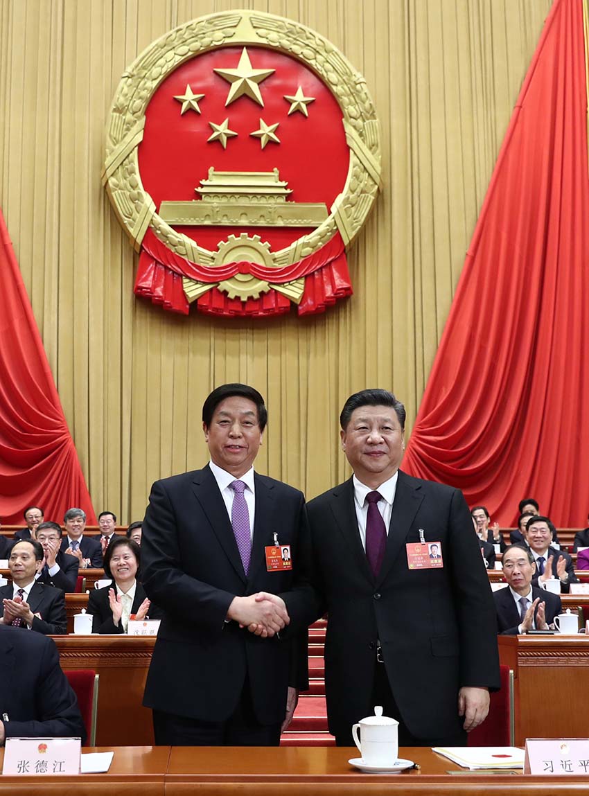 3月17日，十三屆全國人大一次會議在北京人民大會堂舉行第五次全體會議。習近平當選中華人民共和國主席、中華人民共和國中央軍事委員會主席。這是習近平在主席台上同新當選的全國人大常委會委員長栗戰書握手。新華社記者 鞠鵬 攝